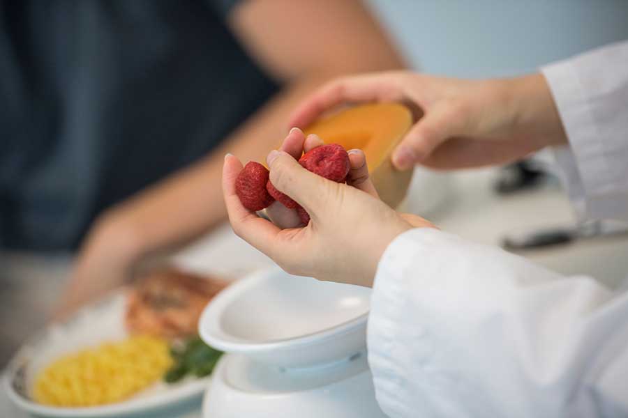 hands holding berries and fruit at a table