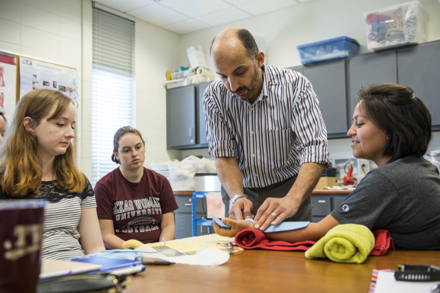 An OT professor demonstrates the correct procedure for aligning the bones of the forearm before wrapping a cast.