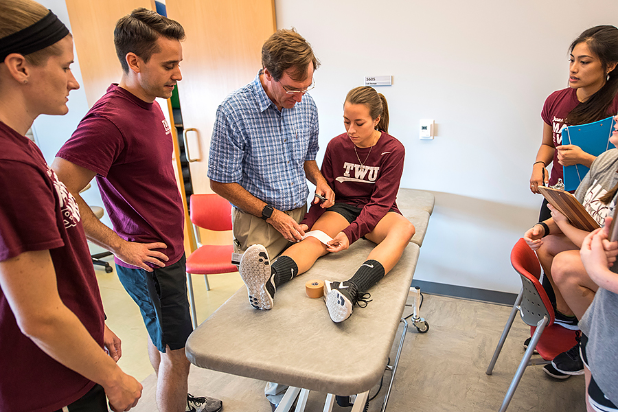 Mark Weber examines a students knee on a training table