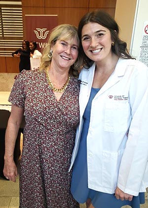 a PT student in white coat stands next to her mother