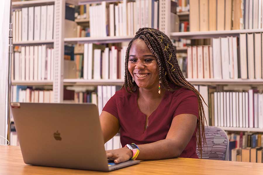 A TWU student works on a laptop in the Denton campus library.	