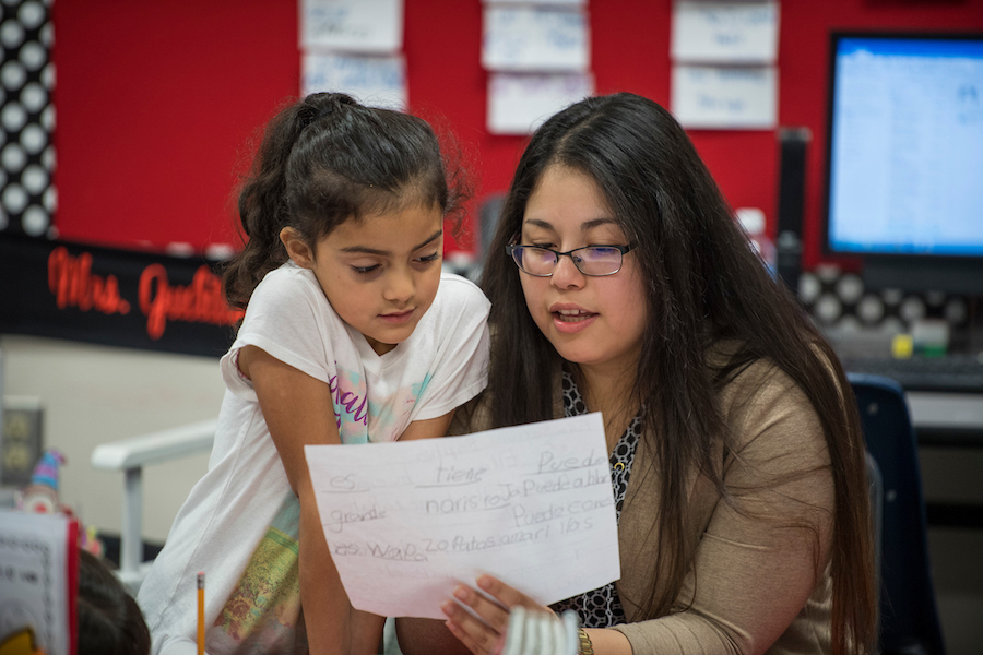 A TWU student teacher and a young girl look over the student's paper.