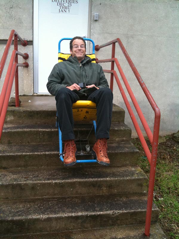 This image shows a man descending stairs in an Evac+Chair.