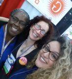 Three women smiling for a group photo.