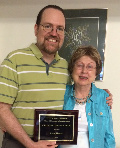 A man and a woman smiling and holding the award.