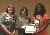 Three women smiling and holding the award certificate.