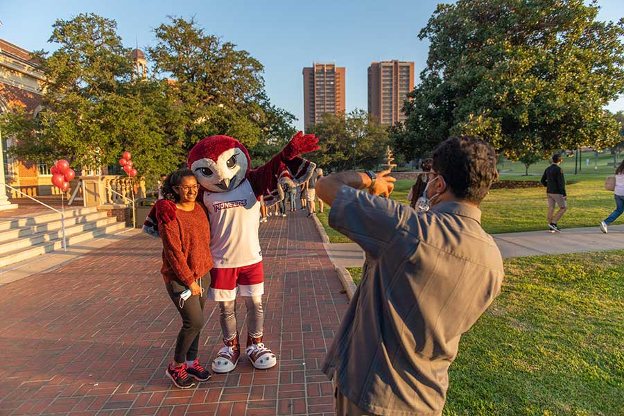 A prospective student takes a photo with Oakley during a Pioneer Preview Day event.	