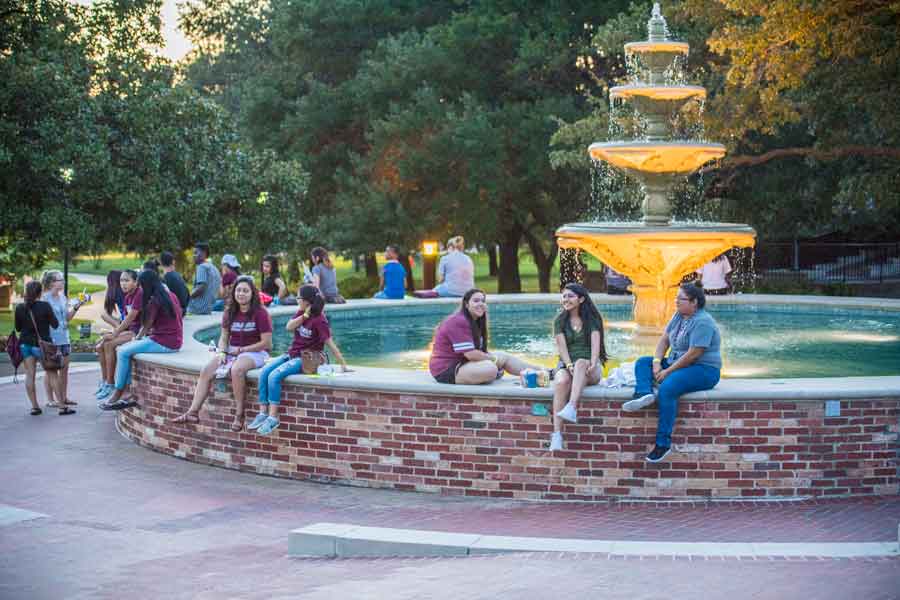 Students gathered at the TWU fountain at twilight.