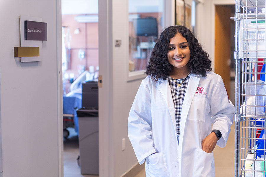 TWU student in a nurses lab coat in a health care setting.