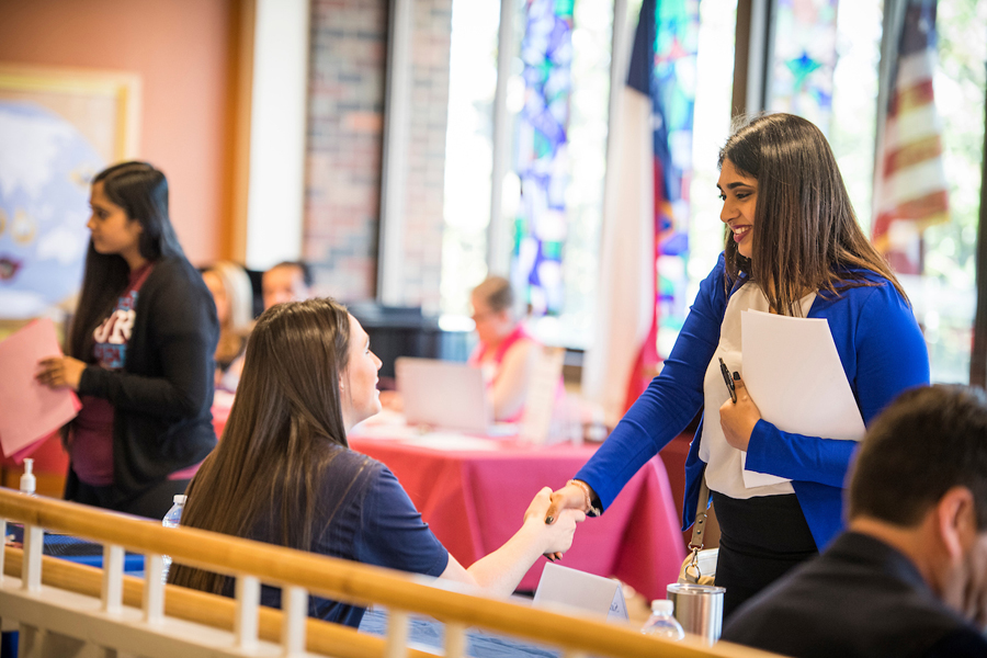 A student dressed in interview attire attends a career and internship fair with her resumes in hand.