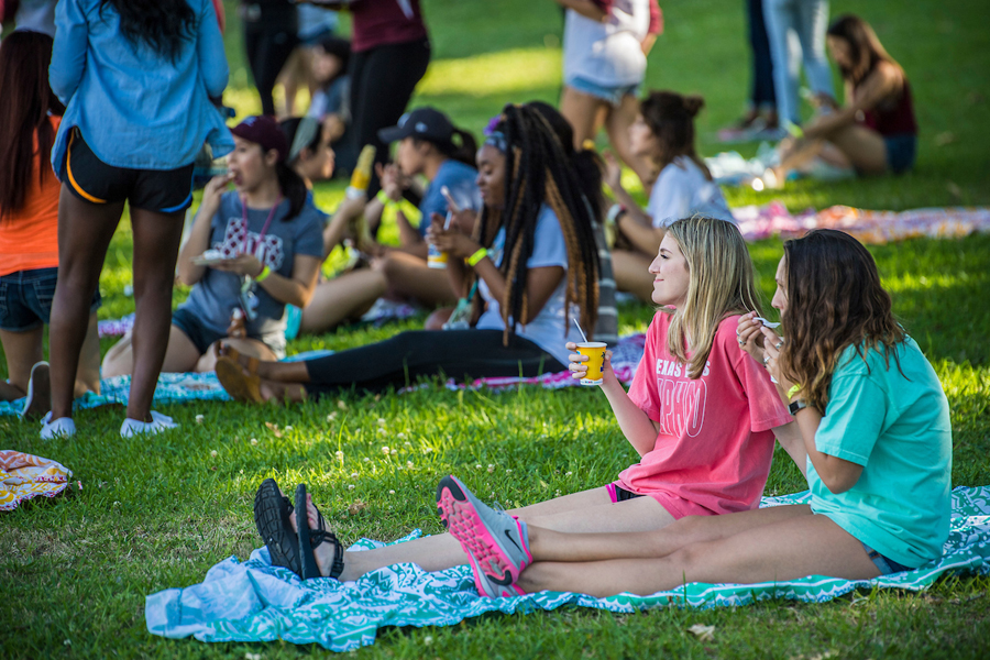TWU students eat snow cones and socialize on picnic blankets at an on-campus event.