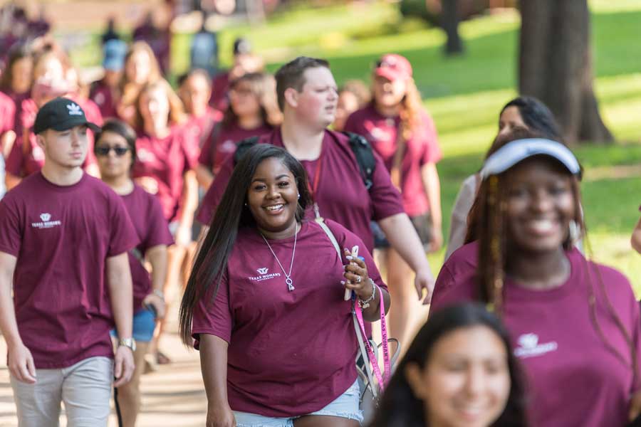 A group tour on TWU's Denton campus with a smiling woman in focus.