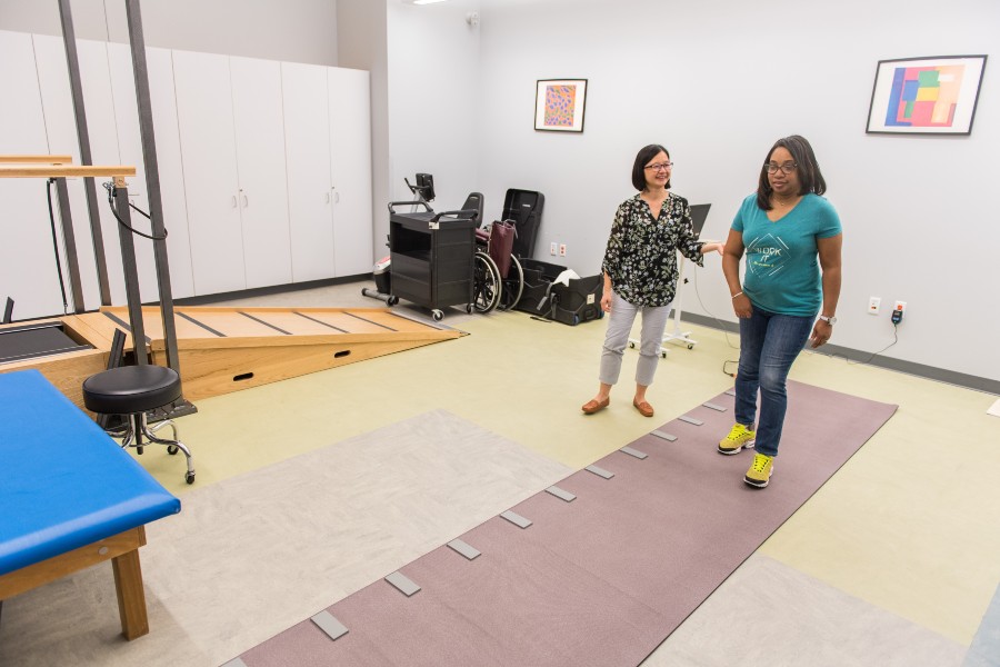 A Stroke Center researcher walking with a patient in a physical therapy exercise.