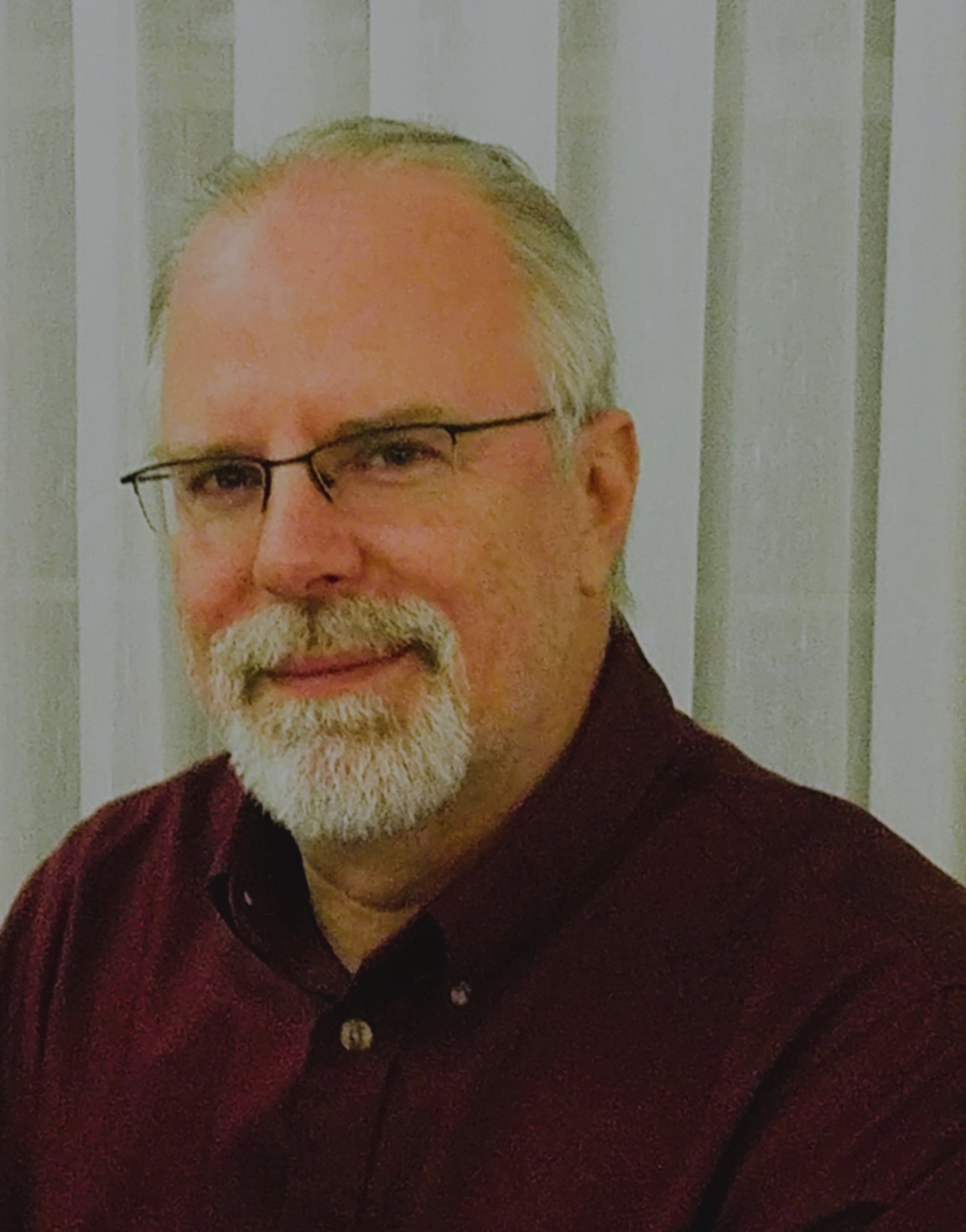 Headshot of Bill Maddox wearing business attire, facing the camera with a neutral background