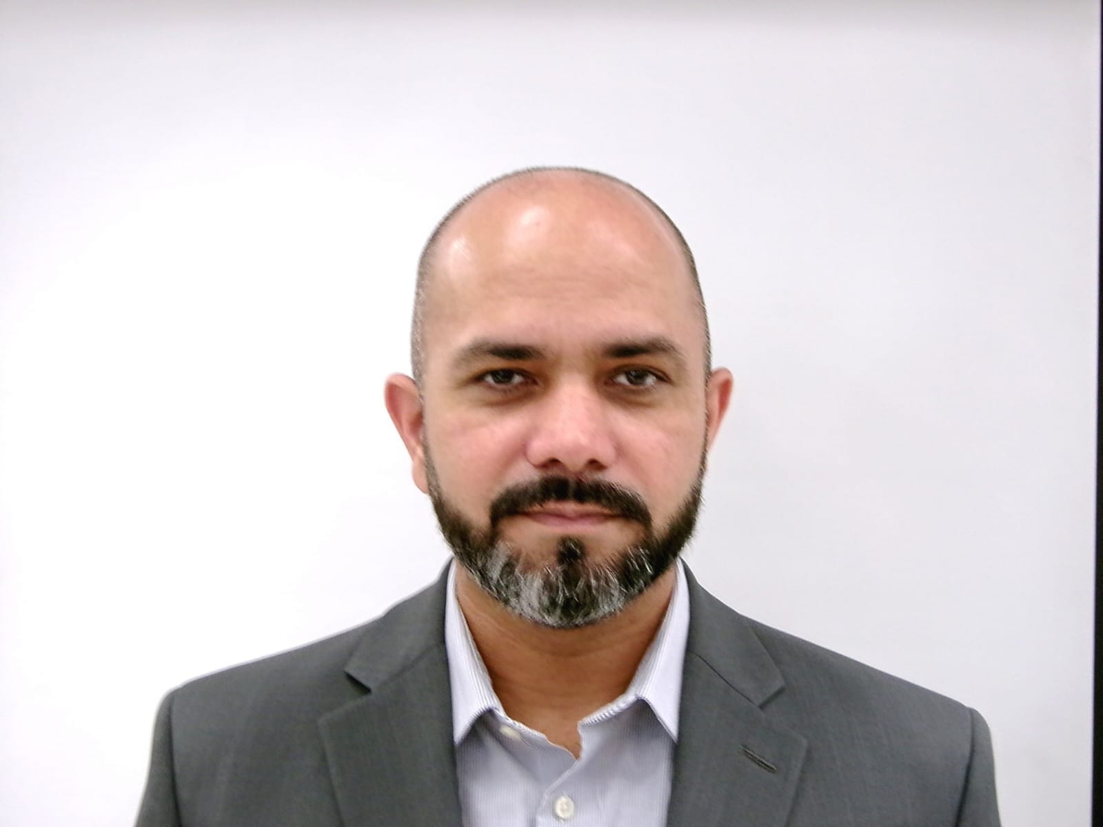 Professional headshot of Naveed Aslam wearing business attire, facing the camera with a neutral background