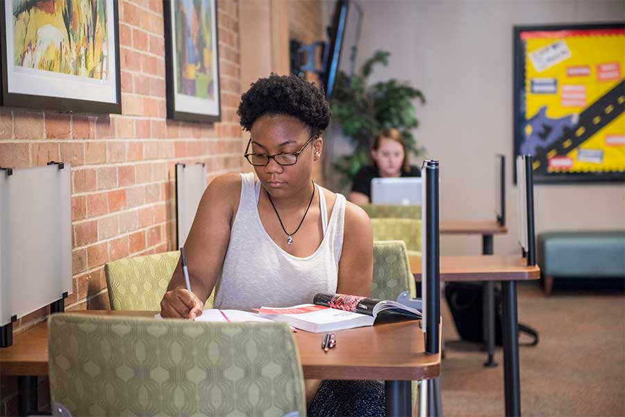 A TWU student studies and reads a textbook on the Denton campus.