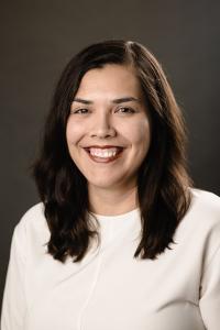 Headshot of Christine Adame. Smiling woman, brown hair, cream sweater