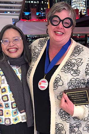 Professor Laura Lee McCartney holds award and stands next to colleague
