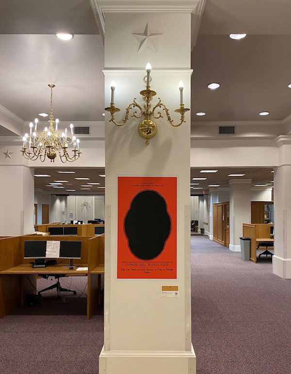 The Forgotten Suffragette art piece hanging on a pillar in the TWU library features a black oval in a red rectangle.