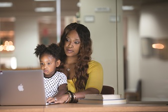TWU student working on a laptop with her daughter