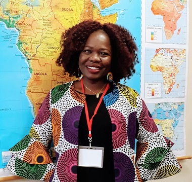 MWGS doctoral student Esther Ajayi-Lowo stands in front of a world map